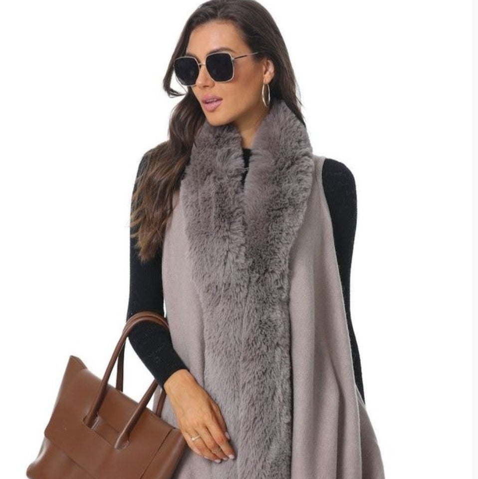 Woman wearing sunglasses, a faux fur vest, and carrying a brown bag.