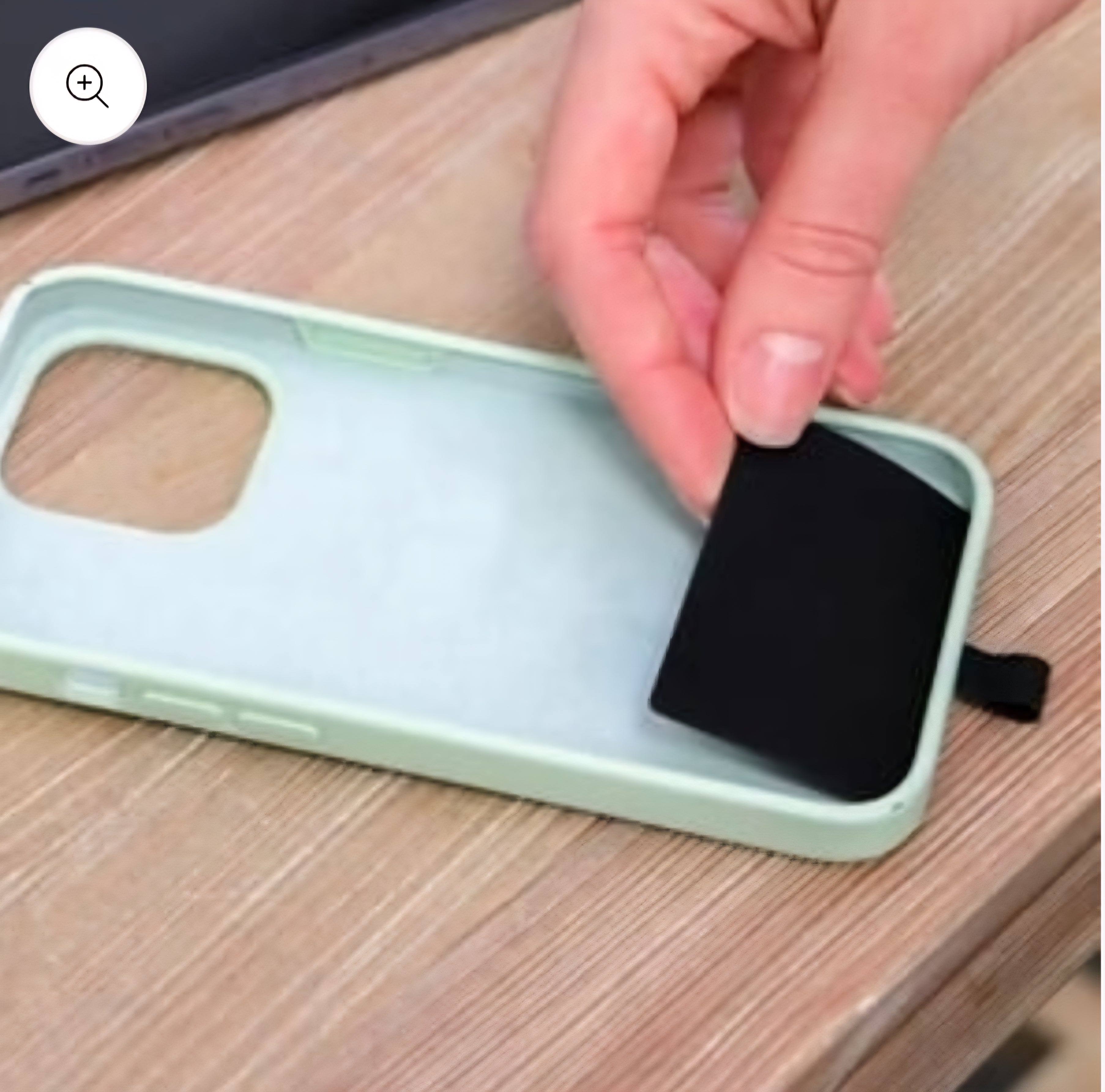 Hand placing a black insert into a mint phone case.