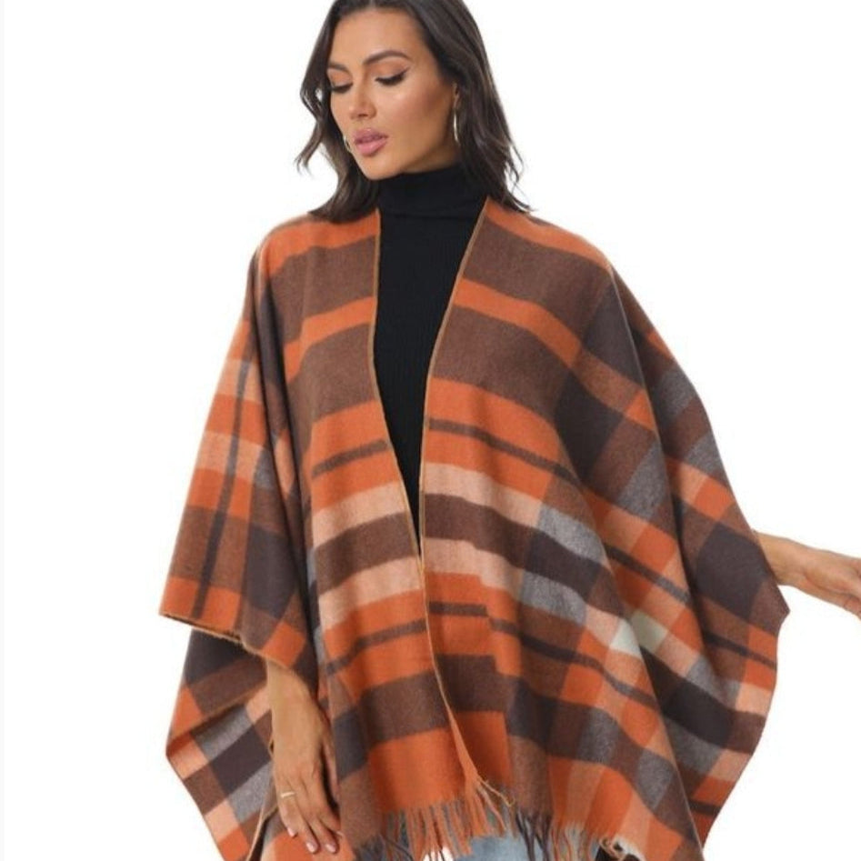 Woman wearing plaid orange and brown poncho.
