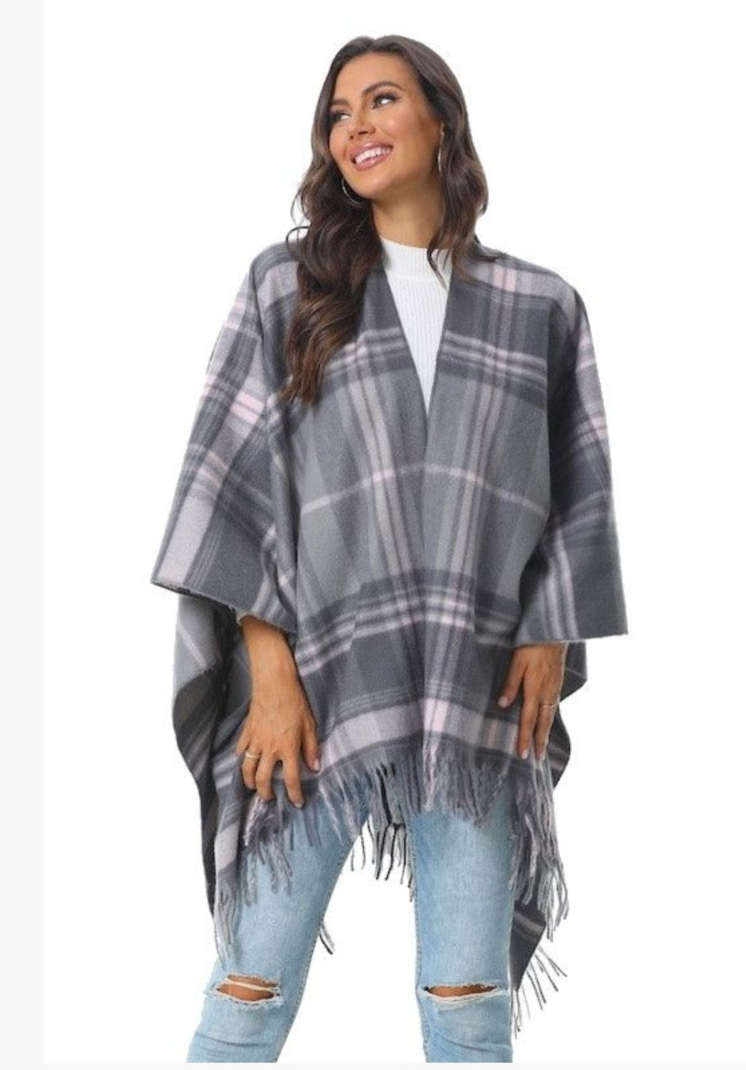 Woman wearing a gray plaid poncho and jeans.