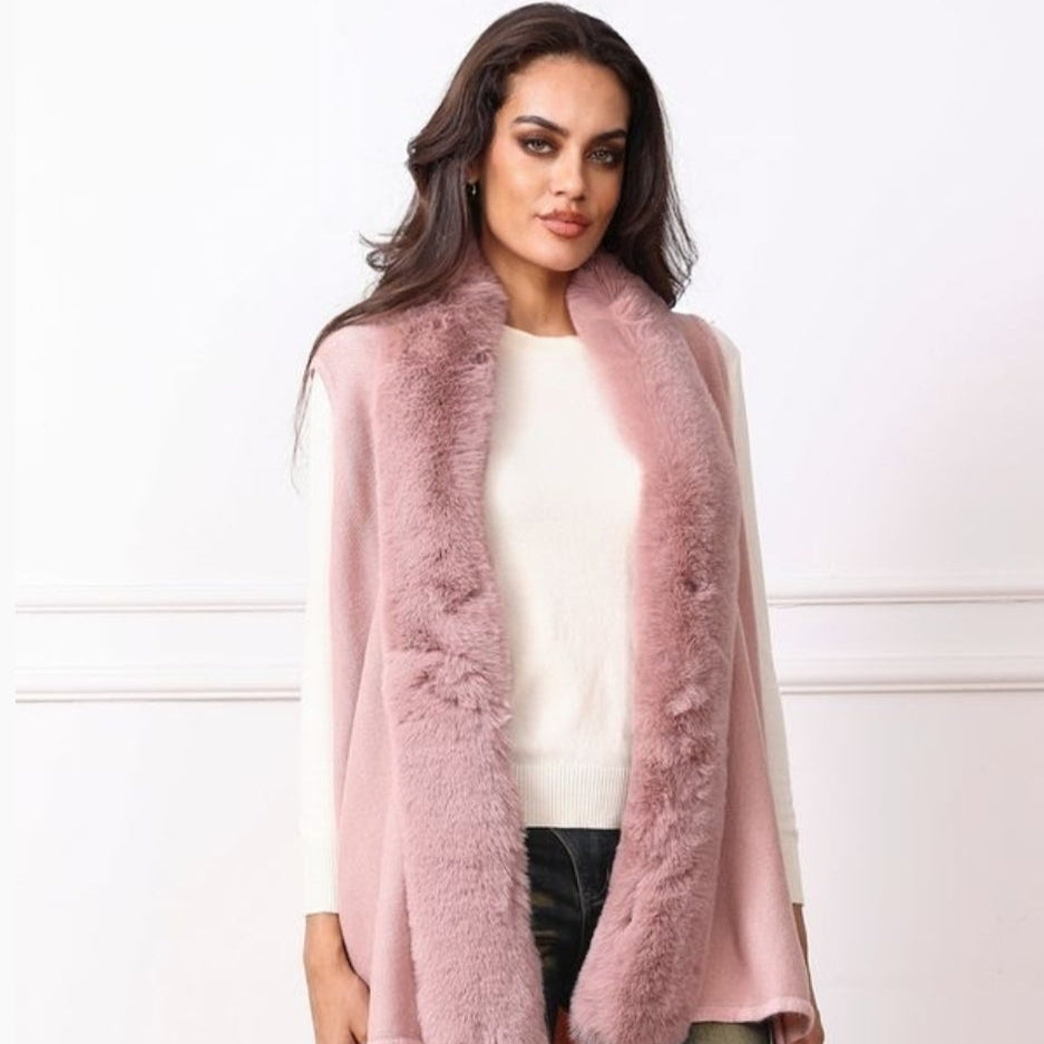 Woman wearing a pink fur-trimmed vest and white sweater.