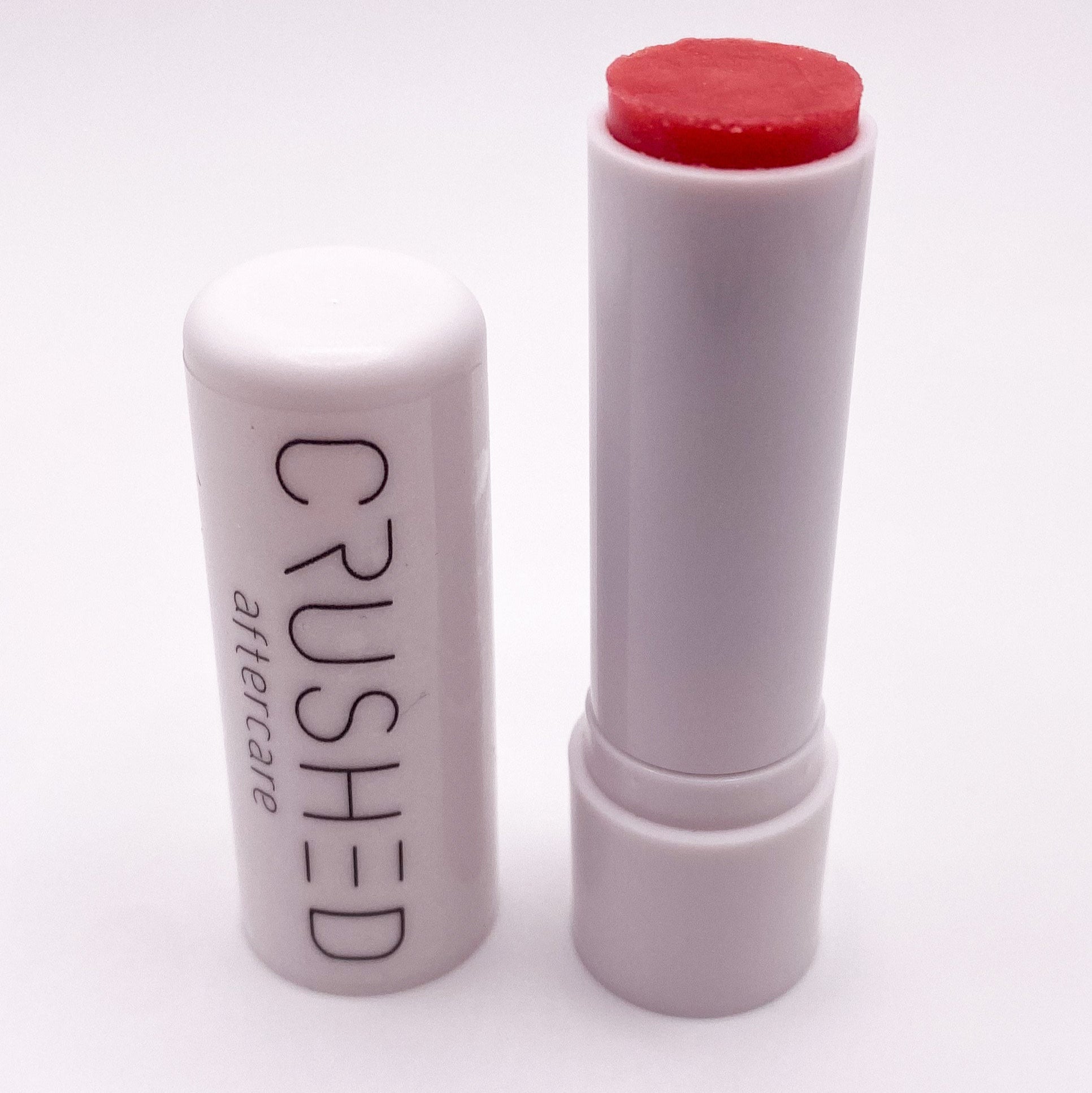 Red lipstick and cap on white background.