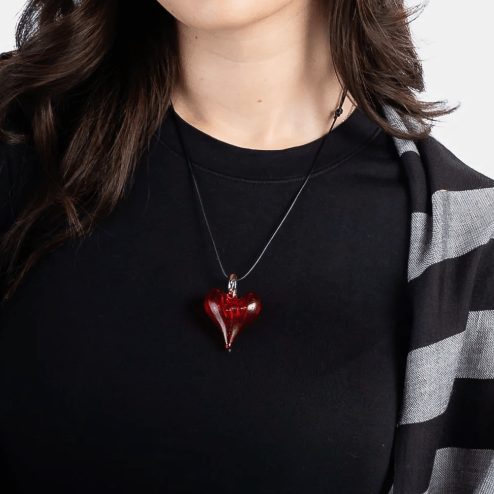 Woman wearing a red heart pendant necklace (Screenshot 2025)