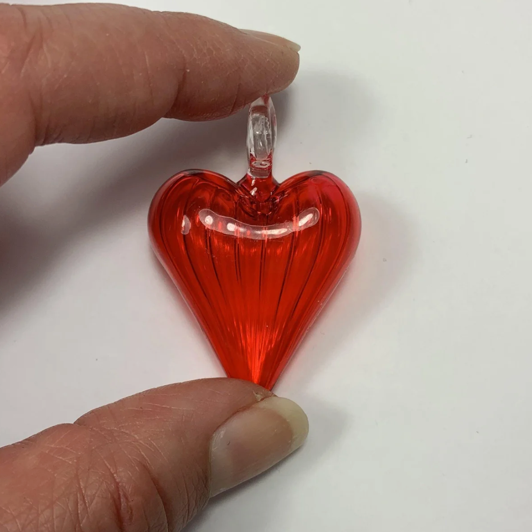 Red glass heart pendant held by hand - Screenshot June 30, 2025.