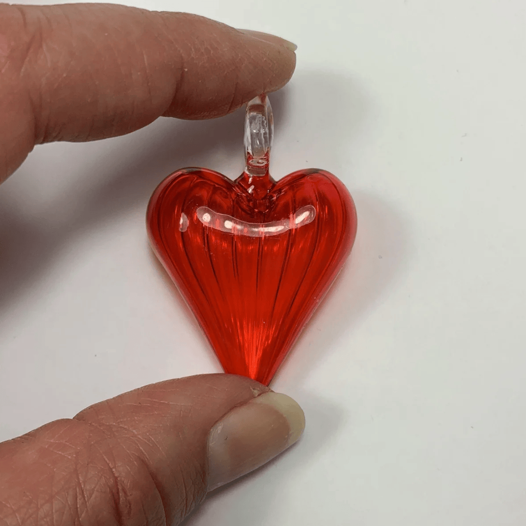 Red glass heart pendant held by hand - Screenshot June 30, 2025.