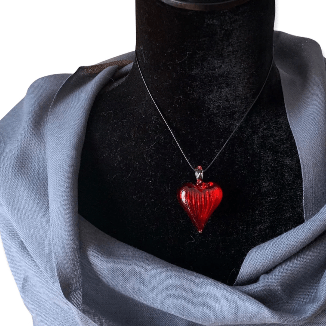 Red glass heart necklace on a black mannequin, screenshot June 30, 2025.