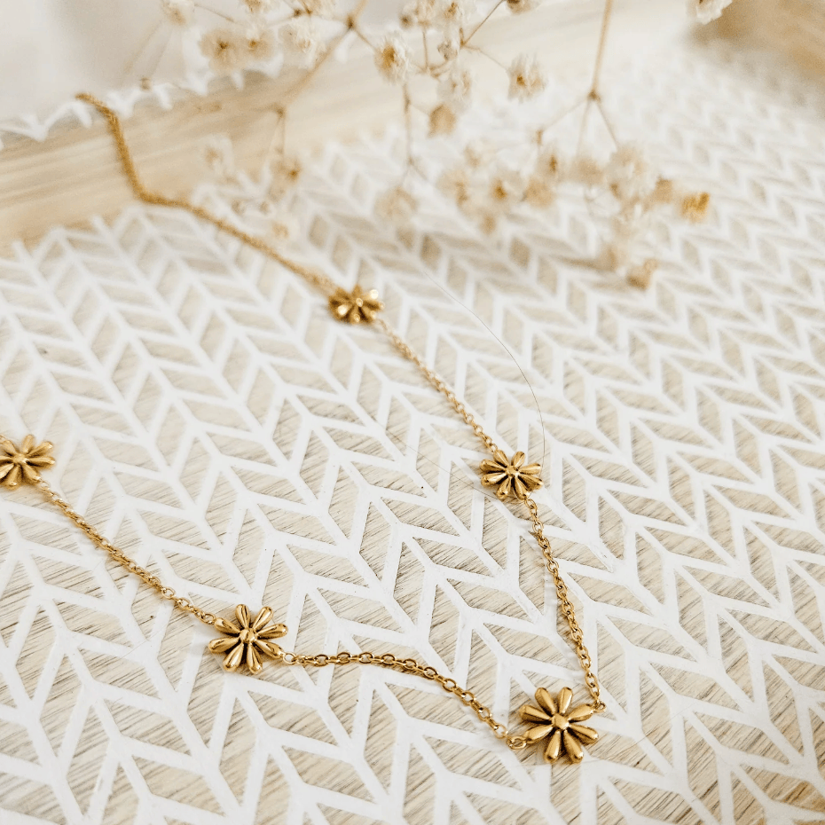 Gold flower necklace on white tray, screenshot July 21, 2025.