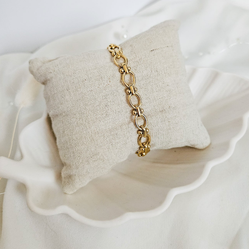 Gold link bracelet on a linen pillow, screenshot July 21, 2025