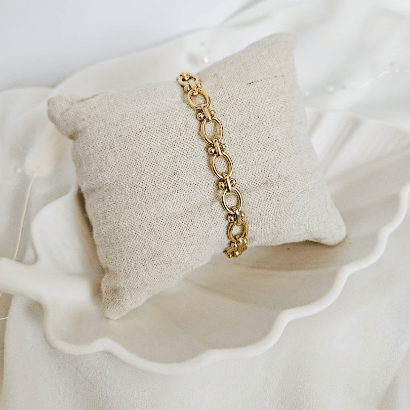 Gold link bracelet on a linen pillow, screenshot July 21, 2025