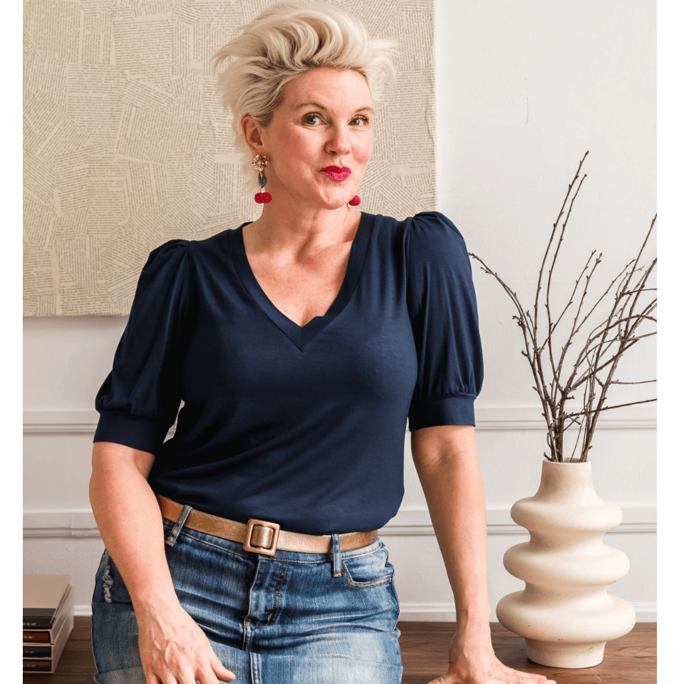 Woman in navy top and denim skirt, screenshot from 2025.