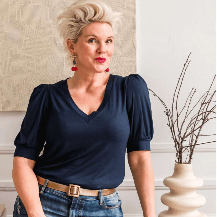 Woman in navy top and denim skirt, screenshot from 2025.