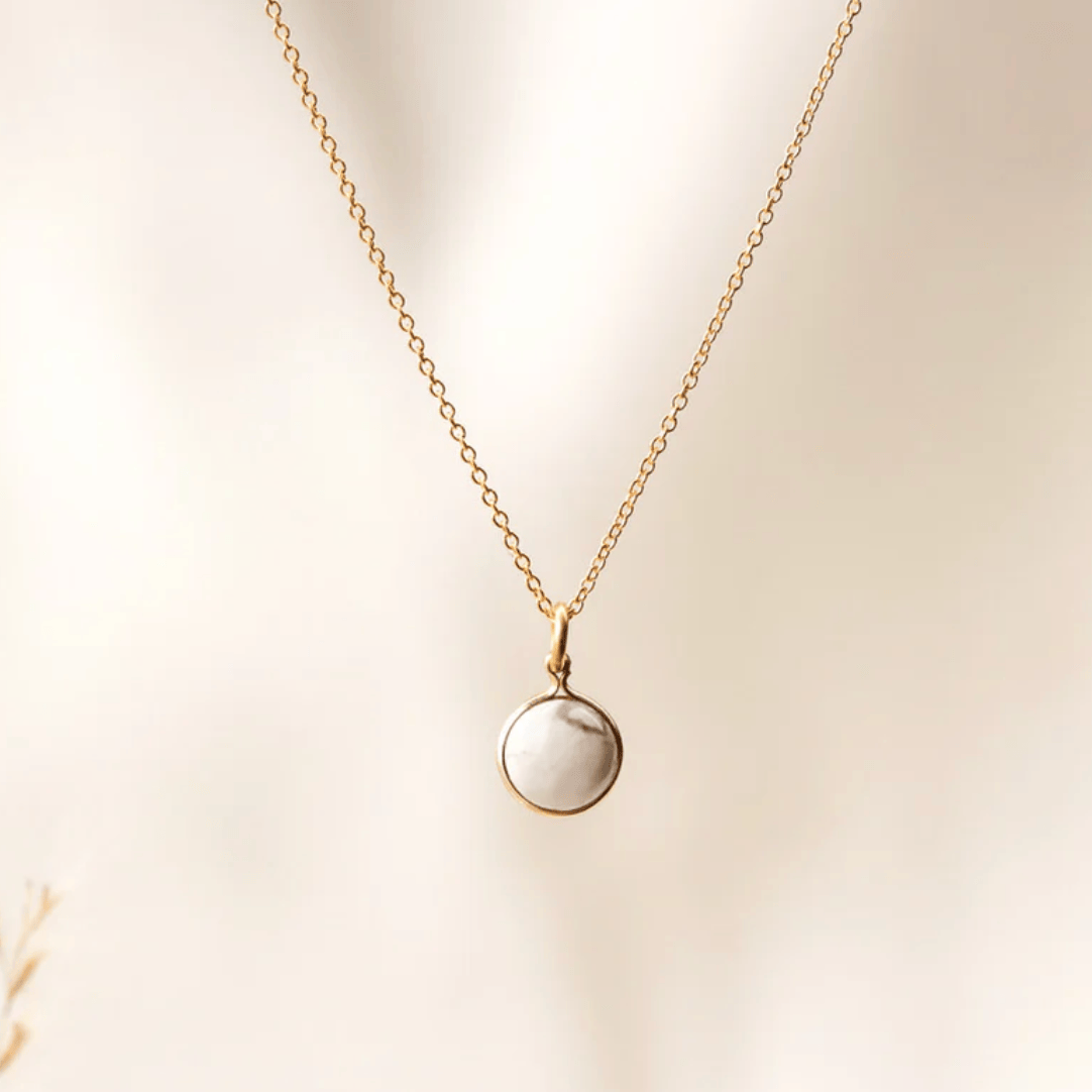 Gold necklace with white stone pendant, screenshot August 27, 2025.
