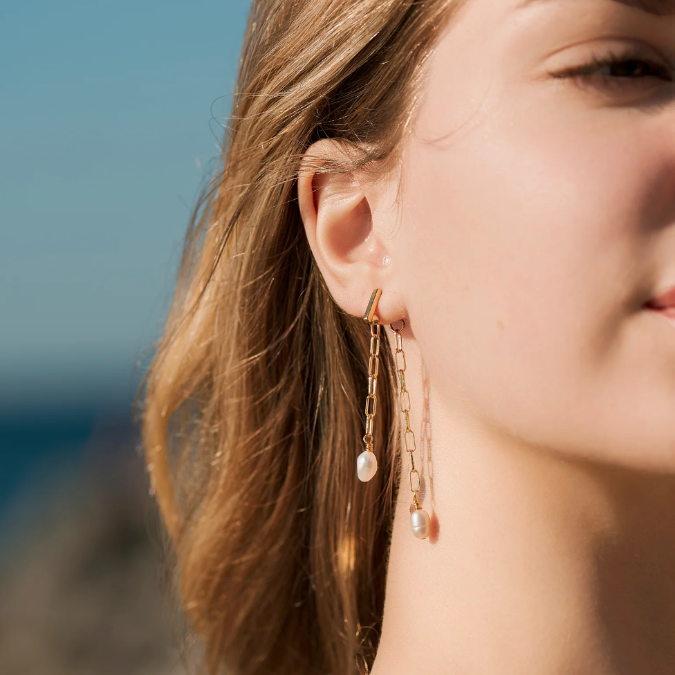 Woman wearing gold chain earrings, screenshot from 2025.