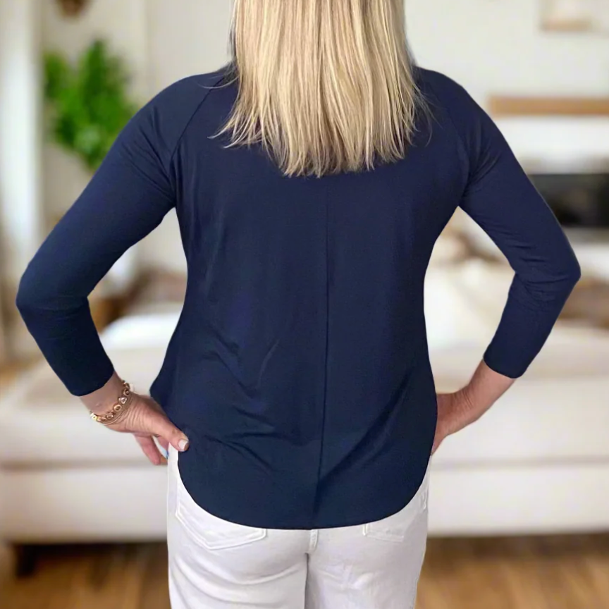 Screenshot of woman in navy blue top and white pants.