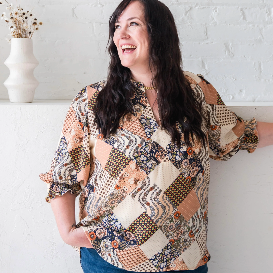 Woman smiling in patchwork blouse, screenshot 2025-09-09.