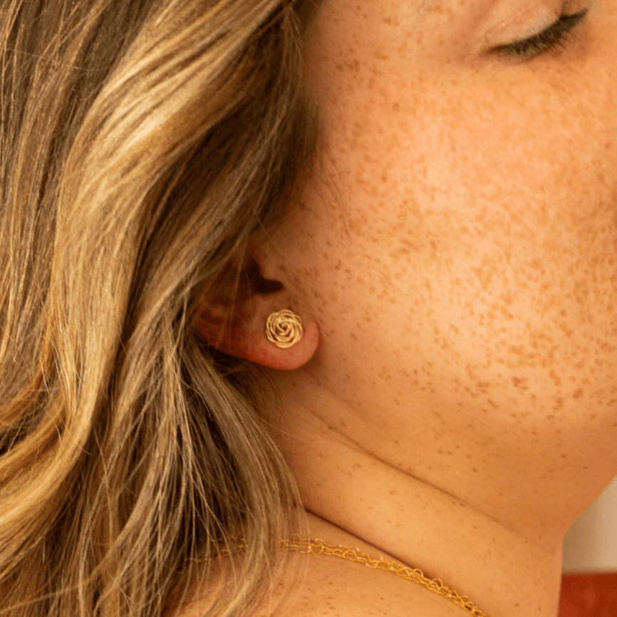 Screenshot of woman wearing gold rose stud earring, Sept 15, 2025