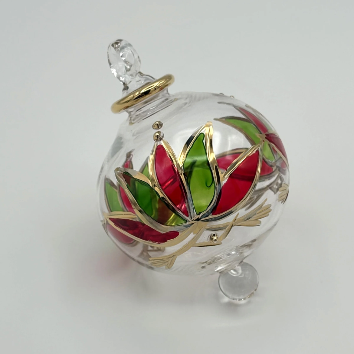 Glass Christmas ornament with red and green floral design.