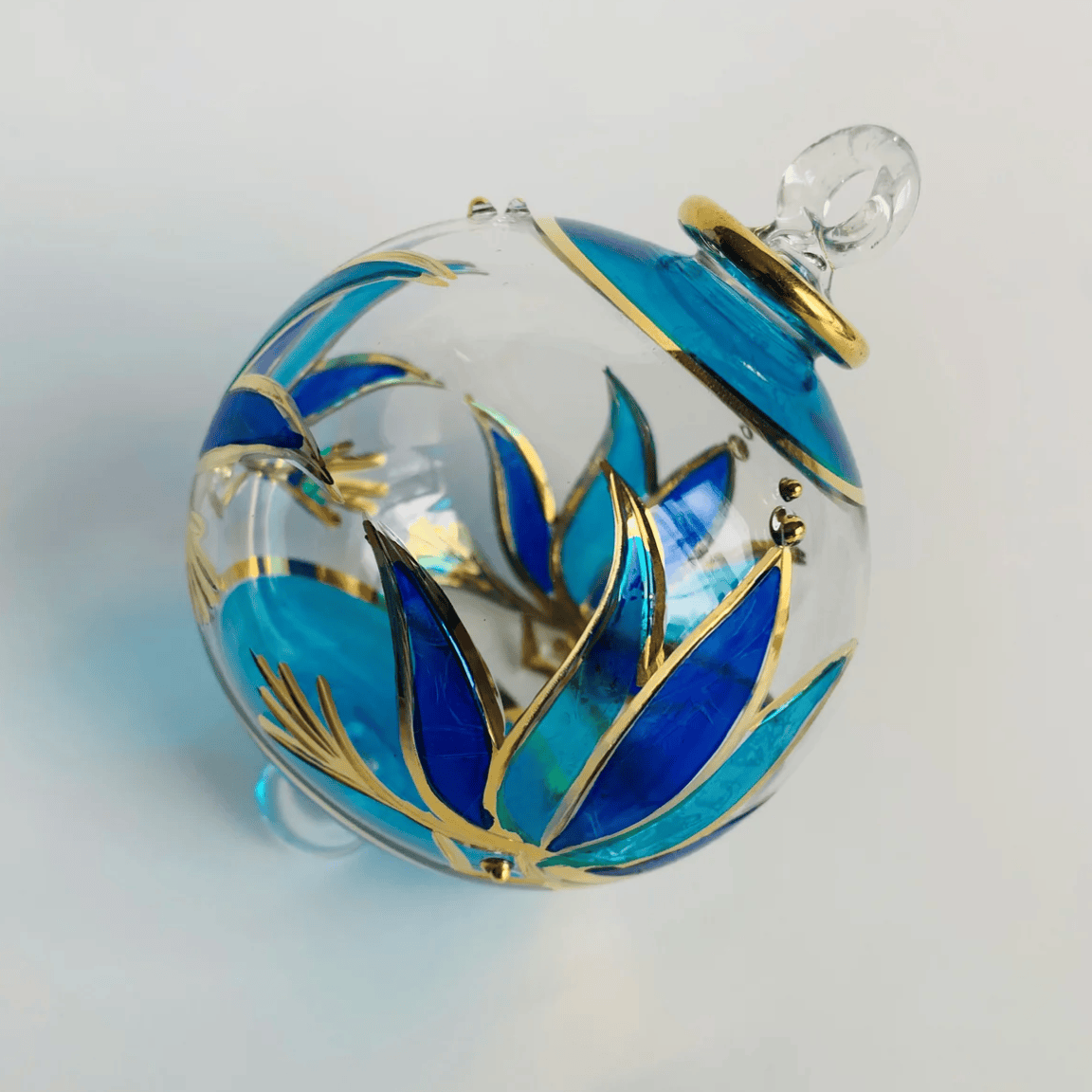 Glass ornament with blue and gold floral design, June 30, 2025.