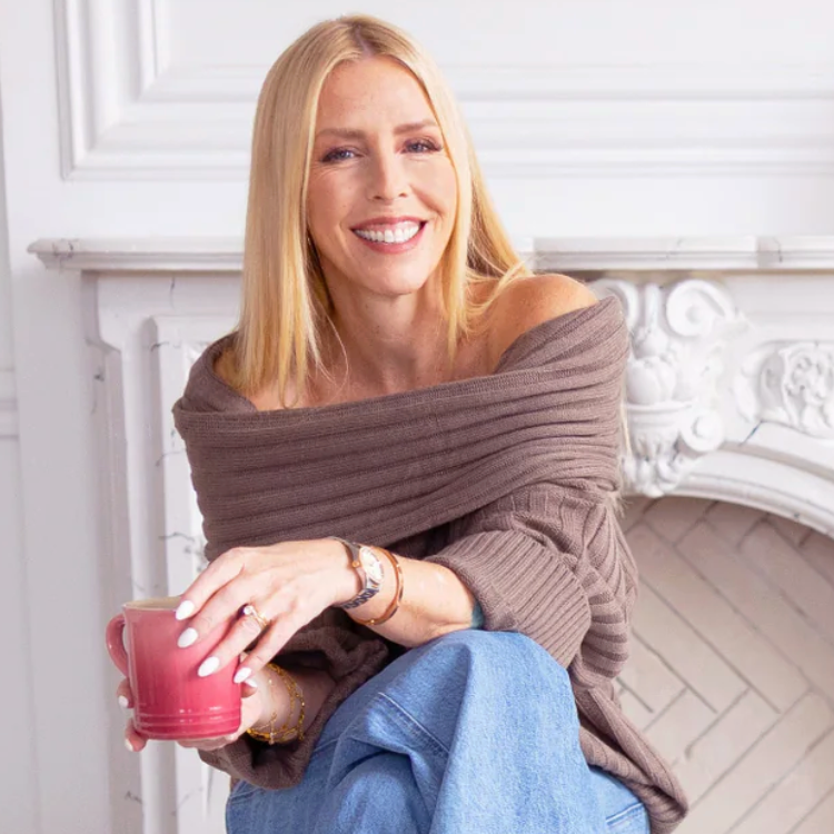 Woman in brown sweater and jeans with coffee, 2025 screenshot.