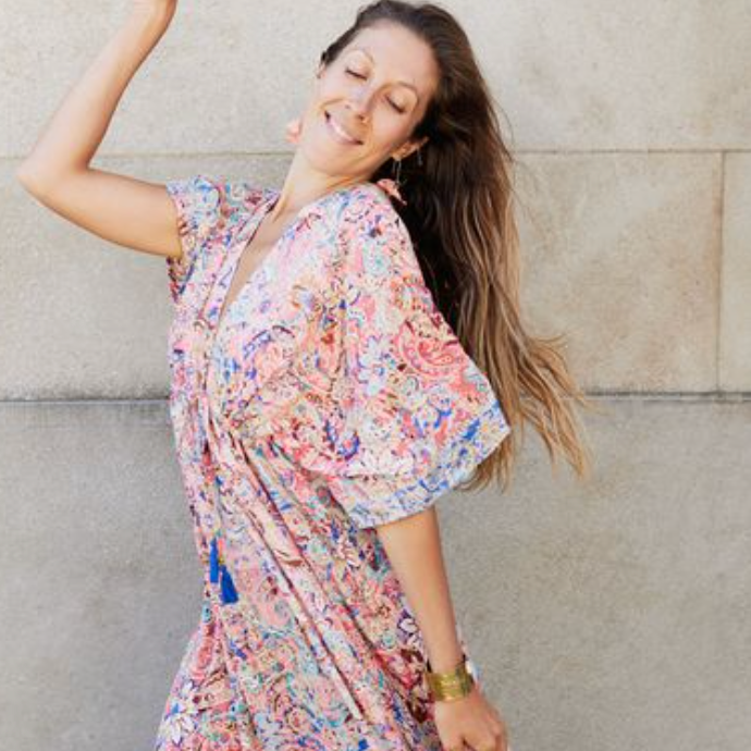 Woman in colorful dress smiling, screenshot from August 16, 2025.