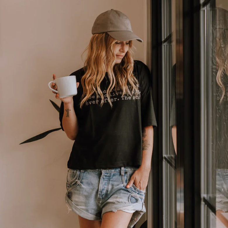 Woman in hat holding mug, screenshot from 2025.