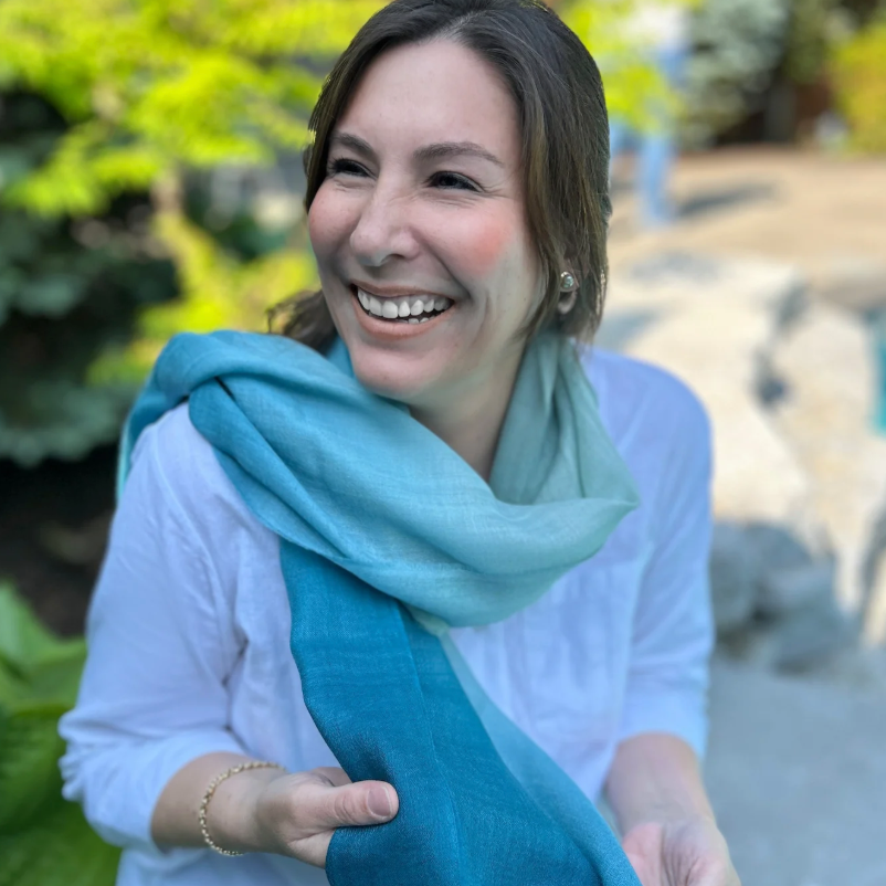 Woman smiling in blue scarf, Sept 15, 2025 screenshot.